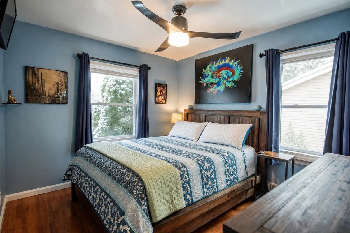 Blue bedroom with a wooden bed and colorful artwork